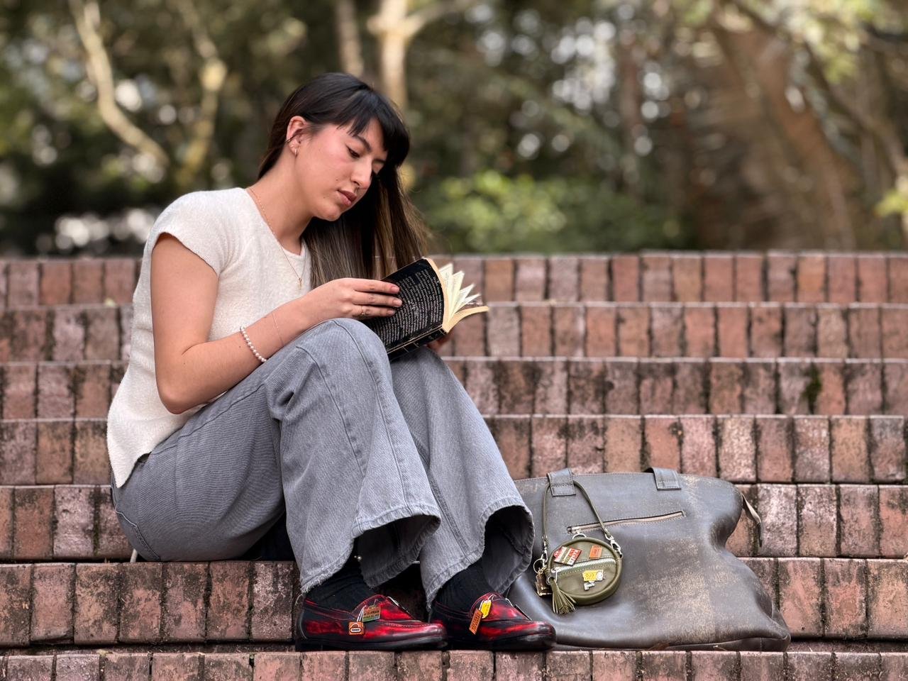 Modelo sentada leyendo, con el bolso y los mocasines de Cotidianidades