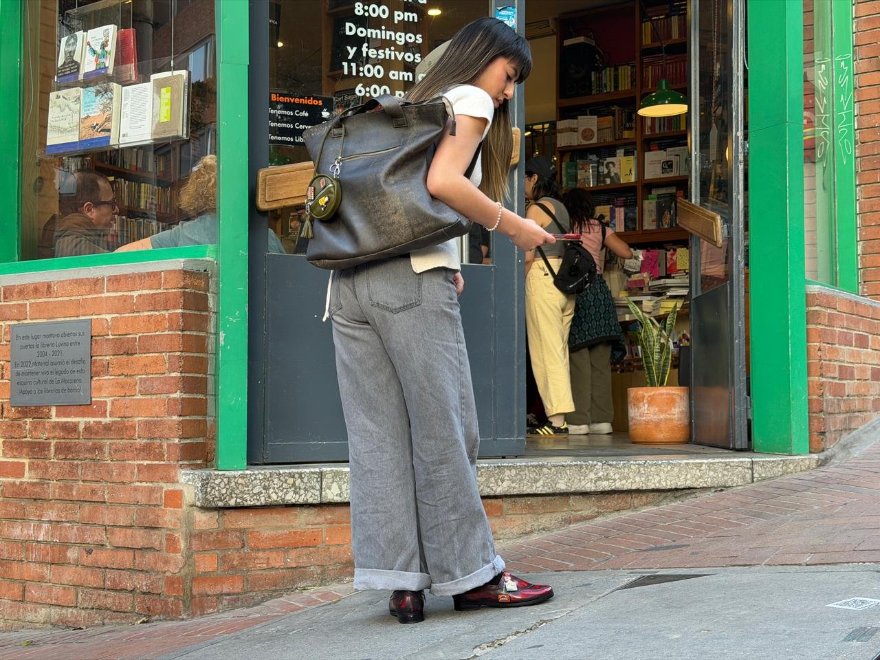 Modelo de cuerpo completo con el bolso y los mocasines de Cotidianidades frente a librer&iacute;a