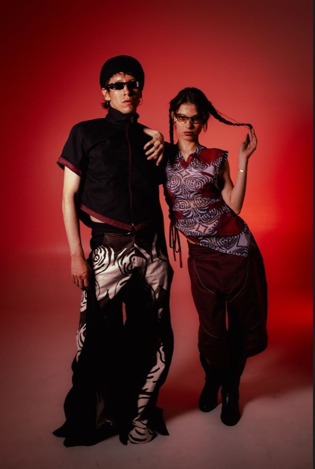 Entre capas: pareja de looks sobre fondo rojo
